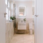 Modern bathroom with vanity unit, LED mirror and neutral tiling