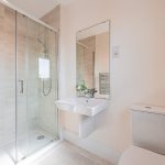 En suite shower room with neutral finish and pedestal sink