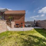 Garden with lawn, patio area and steps leading to raised terrace