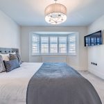 Spacious main bedroom with wall mounted TV and neutral decor