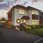 Side exterior of detached hartford home with driveway, garage and twilight lighting
