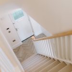 Staircase and entrance hallway with herringbone flooring and front door