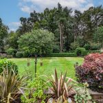 Landscaped south-facing garden with mature planting and private woodland backdrop at 601 Chester Road Sandiway