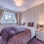 Double bedroom at 11 Sandington Drive, Cuddington, with floral wallpaper, bay window and warm bedside lighting.