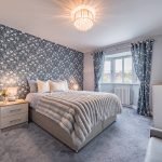 Principal bedroom at 11 Sandington Drive, Cuddington, with floral feature wall, bay window and soft grey furnishings.