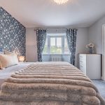 Principal bedroom at 11 Sandington Drive, Cuddington, with floral feature wall, bay window and access to the en-suite shower room.