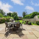 Rear garden at 211 Hartford Road, Davenham, showing lawn, patio seating, potted plants and the rear of the house.