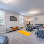 Spacious lounge at 18 Brooke Avenue, Winnington, with leather seating, bright window shutters and a dedicated home office area.