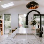 Contemporary kitchen detail featuring quartz worktops, designer tap and open-plan family living beyond.
