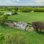 Elevated aerial view of Brooklyn Cottage revealing landscaped gardens and open countryside surrounding the property.