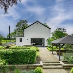 Rear garden and covered outdoor entertaining area at Brooklyn Cottage in Lostock Green with formal landscaping and open views.