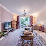 Spacious living room with feature fireplace and bi-fold doors opening onto the rear garden at 1 Earls Way, Kingsmead.