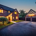 Twilight front elevation with detached double garage and generous driveway.