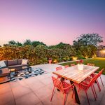 Contemporary patio and outdoor entertaining area at dusk overlooking the mature rear garden and detached garden room.