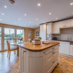 Spacious kitchen at The Poplars with central island, Aga, parquet flooring and windows overlooking the front of the property.