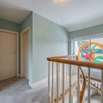 Light-filled first-floor landing at The Poplars with glazed outlook and open staircase below.