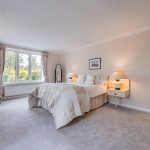 Spacious ground-floor bedroom at The Poplars with a broad window overlooking the garden and landscape beyond.