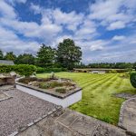 Landscaped rear garden and terrace at The Poplars with generous lawns and established planting.