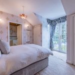 Principal bedroom at The Poplars with generous proportions, fitted storage and glazed doors bringing in natural light.