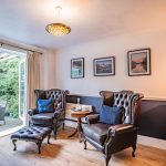 Separate family room with leather wingback chairs, wood flooring and French doors opening onto the rear garden.