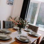 Dining table set for six with fresh flowers and upholstered chairs at 3 Monarch Drive