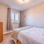 Alternative view of the double bedroom showing the window, timber furniture and neutral décor at 3 Monarch Drive