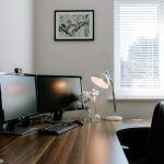 Home office workspace with a large wooden desk, dual monitors and a window at 3 Monarch Drive