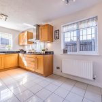 Bright kitchen with oak cabinetry, dark worktops, tiled flooring and space for dining at 3 Monarch Drive