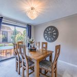 Dining room with wooden table, decorative pendant lighting and sliding patio doors overlooking the rear garden.