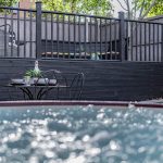 Garden lifestyle view across the hot tub towards outdoor dining furniture and elevated decked seating.