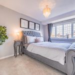 Beautifully presented principal bedroom with soft grey interiors, upholstered bed and decorative pendant lighting.