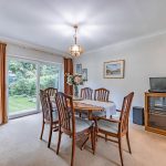 Dining room with six-seat wooden dining table and sliding patio doors opening onto the established rear garden.
